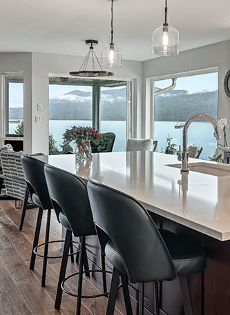 white kitchen island with black stools and hanging lights view of back of stools